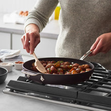 Black nonstick skillet with food, wooden spatula inside