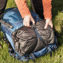 Open 50L hiking backpack with zipper and top flap; hands adjusting the opening