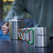 Stainless steel coffee kettle and mugs with colorful handles on table