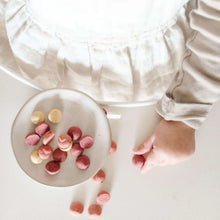 Bowl of yogurt smoothie melts with pink and white pieces, with spoon and hand
