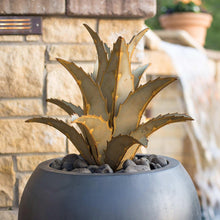 Metal agave sculpture with spiky pale gold leaves in a round gray outdoor planter