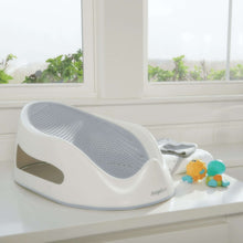 Gray baby bath support insert in white base, placed in a bathtub