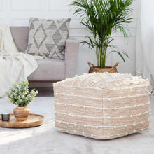 Woven wool pouf in natural cream with horizontal stripe texture and pom accents.