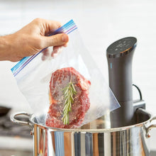 Anova precision sous vide cooker next to a vacuum-sealed steak in a pot