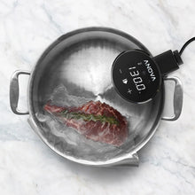 Anova precision sous vide cooker clipped to a pot, circulating water around food