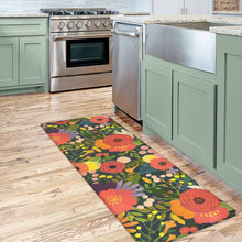 Kitchen runner rug with bright floral print on dark green background, long and narrow.