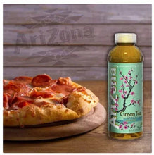 AriZona green tea bottle with amber liquid beside pizza on plate