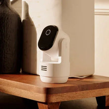 Indoor pan-tilt security camera on shelf with white body and black front lens cover