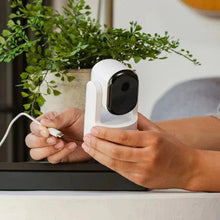 Indoor pan-tilt security camera with hand connecting cable to the white base