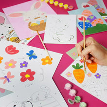 Easter paint-by-number cards spread out with brush and multiple colored paint pots