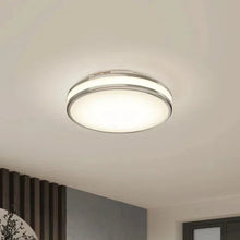 LED flush mount ceiling light with circular silver rim and frosted lens, lit.