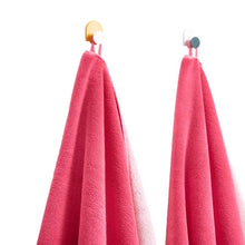 Pink bath towels with multicolor striped trim, hanging on hooks