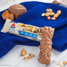 Caramel chocolate nut roll snack bar on blue cloth with nut and chocolate pieces