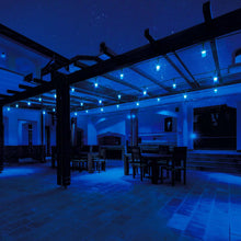 Blue string light bulbs under a pergola ceiling on black cables