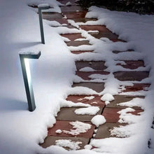Outdoor pathway light posts with blue glow along a snowy stone walkway