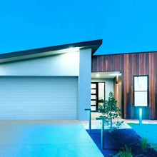Outdoor pathway light posts with blue illumination along a driveway edge