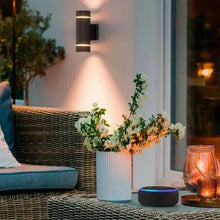 Outdoor wall sconce with dark metal finish and two glowing light panels, warm light.