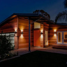 Black outdoor wall sconces casting warm light on a home exterior walkway