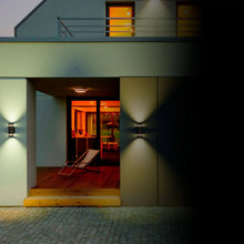 Pair of outdoor wall sconces with dark metal housings, warm light flanking a doorway.