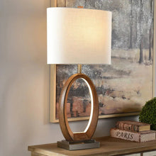 Table lamp with beige fabric shade and oval wood-tone base on tabletop