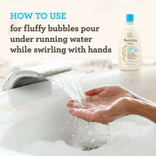 Aveeno baby bubble bath bottle beside hands rinsing in tub under running water