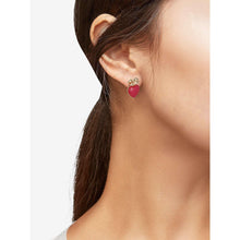 Gold-tone heart and bow stud earrings with red heart drops on model ear