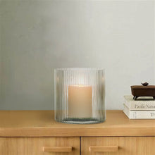 Green ribbed glass hurricane candle holder with lit candle inside, round open top