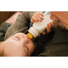 Ivory baby bottle with slow-flow silicone nipple used to feed an infant