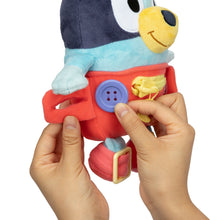 Plush baby Bluey dress toy close-up, red overalls with purple button and yellow zipper pull