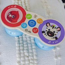 Close-up of blue two-drum toy with red sea-creature and purple animal face panels