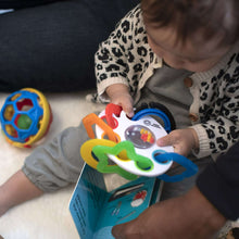 Baby playing with activity ring toy featuring colorful handle pieces and mirror