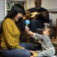 Baby music toy whale held by child, with parents and toddler playing at home