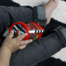 Baby activity rattle with clear chamber and red rings, gripped by small hands