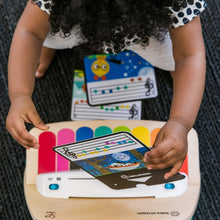 Baby hands using touch piano toy with bright color keys and screen