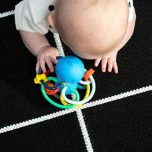 Baby holding blue ocean teether and rattle toy with colorful rings and bead