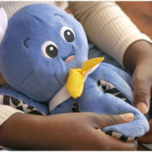 Blue octopus plush toy held in hands, yellow bow and embroidered face