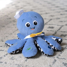 Blue octopus plush toy lying down with yellow bow and big friendly eyes