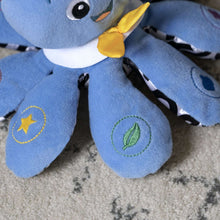 Blue octopus plush tentacles with stitched star and leaf patches, bow at neck