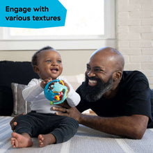 Baby holding teal sensory rattle ball with dangling colorful parts