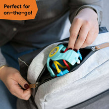 Teal sensory rattle ball clipped into a carry bag, showing colorful rings