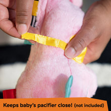 Hands fastening the pink seahorse plush soother pacifier strap with yellow ribbon