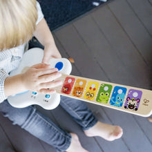 Baby toy guitar in hand, white body with blue buttons and colorful animal keys