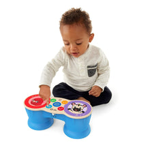 Baby seated playing with blue two-drum musical toy with animal face sound panels