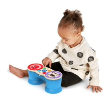 Infant playing with blue two-drum musical toy with colorful icon buttons