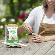 Plantable seed starting pot with soil and seedlings beside 8-pack seed pot box