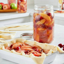 Wide-mouth mason jar filled with fruit preserves, clear glass jar with lid