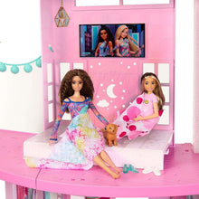Dollhouse bedroom with two seated fashion dolls and a small pet on bed