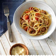 Gluten-free spaghetti bowl with meatballs, tomato slices, and grated cheese