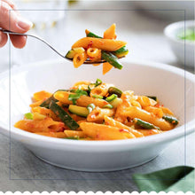 Bowl of penne pasta with orange sauce, green onions, and carrots