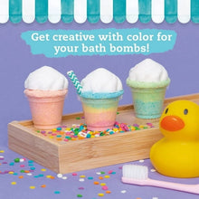 Three pastel bath bomb cupcakes on a wooden tray with sprinkles and a yellow duck mold
